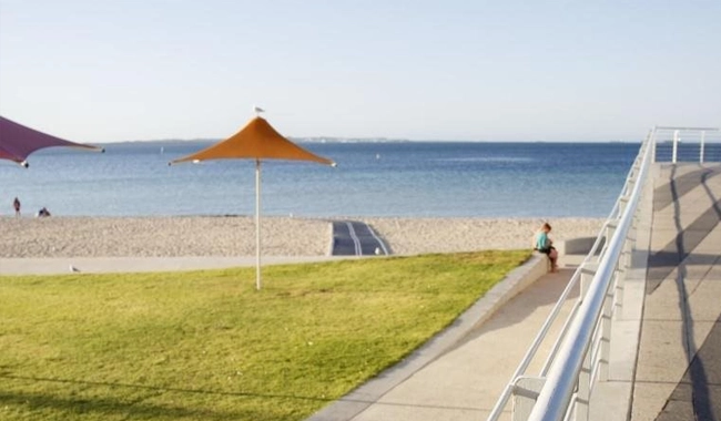 a person sitting on a bench next to a beach