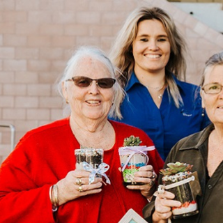Library staff and customers holding decorated succulent jars after a workshop.