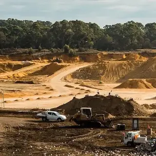 a construction site with sand piles and trees