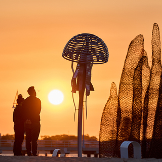 Silhouettes of people beside the Castaways sculptures at sunset along the Rockingham Foreshore.