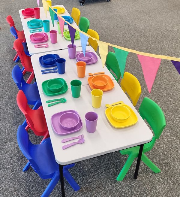 displayed party kit avaliable for hire, includes table with plates, utensils and cups, with bunting overhead