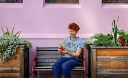 a woman sitting on a bench holding a plant