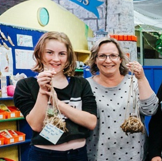 Library staff standing together holding kokedama plant creations during a group activity.