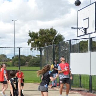 a group of people walking on an outdoor basketball court