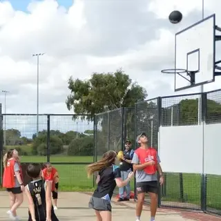 a group of people walking on an outdoor basketball court