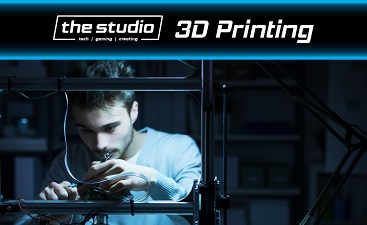 Male person in front of a 3D printer holding a pen.