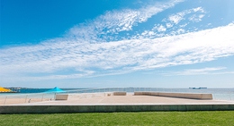 a concrete platform with a blue umbrella on the side of the water