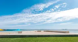 a concrete platform with a blue umbrella on the side of the water