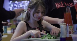 a woman cutting cucumber on a plate