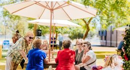 a group of people sitting at a table under an umbrella