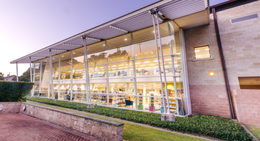 Exterior of Rockingham Library at dusk, showing large glass windows lit from inside.