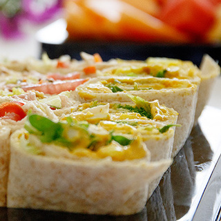 Platter of sliced wrap sandwiches filled with vegetables and chicken, arranged for catering or training.