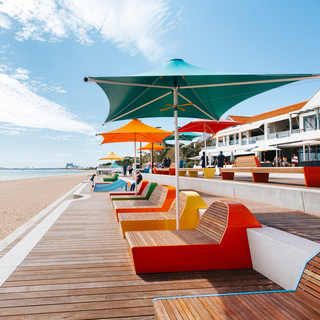 Rockingham Foreshore boardwalk with colourful seating and shade umbrellas beside the beach and ocean.