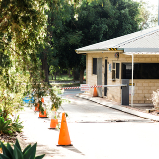 Millar Road Landfill weighbridge office with entry boom gate, warning signs, and traffic cones along the driveway.