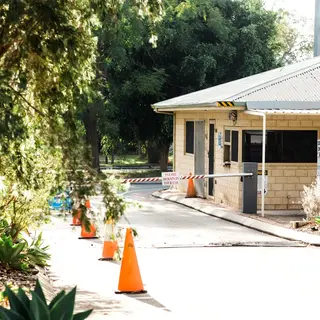Millar Road Landfill weighbridge office with entry boom gate, warning signs, and traffic cones along the driveway.