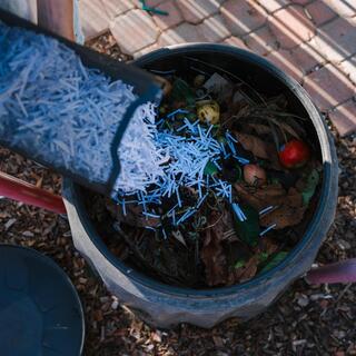a person pouring white straw into a trash can