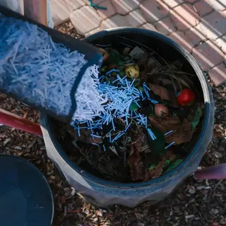 a person pouring white straw into a trash can