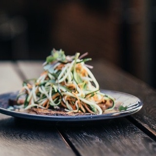 a glass of yellow liquid next to plates of food