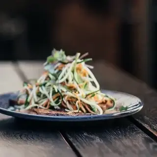 a glass of yellow liquid next to plates of food