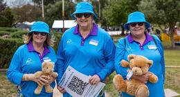 a group of women wearing blue shirts and holding teddy bears
