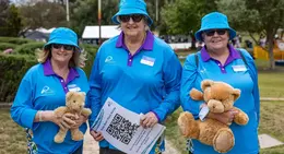 a group of women wearing blue shirts and holding teddy bears