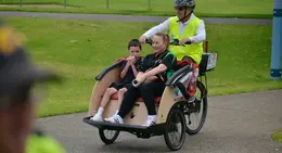 a man riding a bicycle with a woman and a boy
