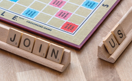 Scrabble board and Scrabble letters spelling out 'join us'